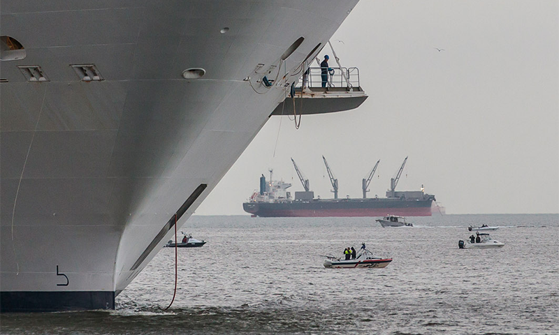 Profile of ship's bow with small boats and other ship in backgrouond